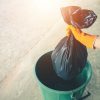 Close-Up Of Woman Putting Garbage Bag In Plastic Container